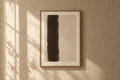 Basalt Framed Print — A dark espresso column standing off-centre on an unbleached ground